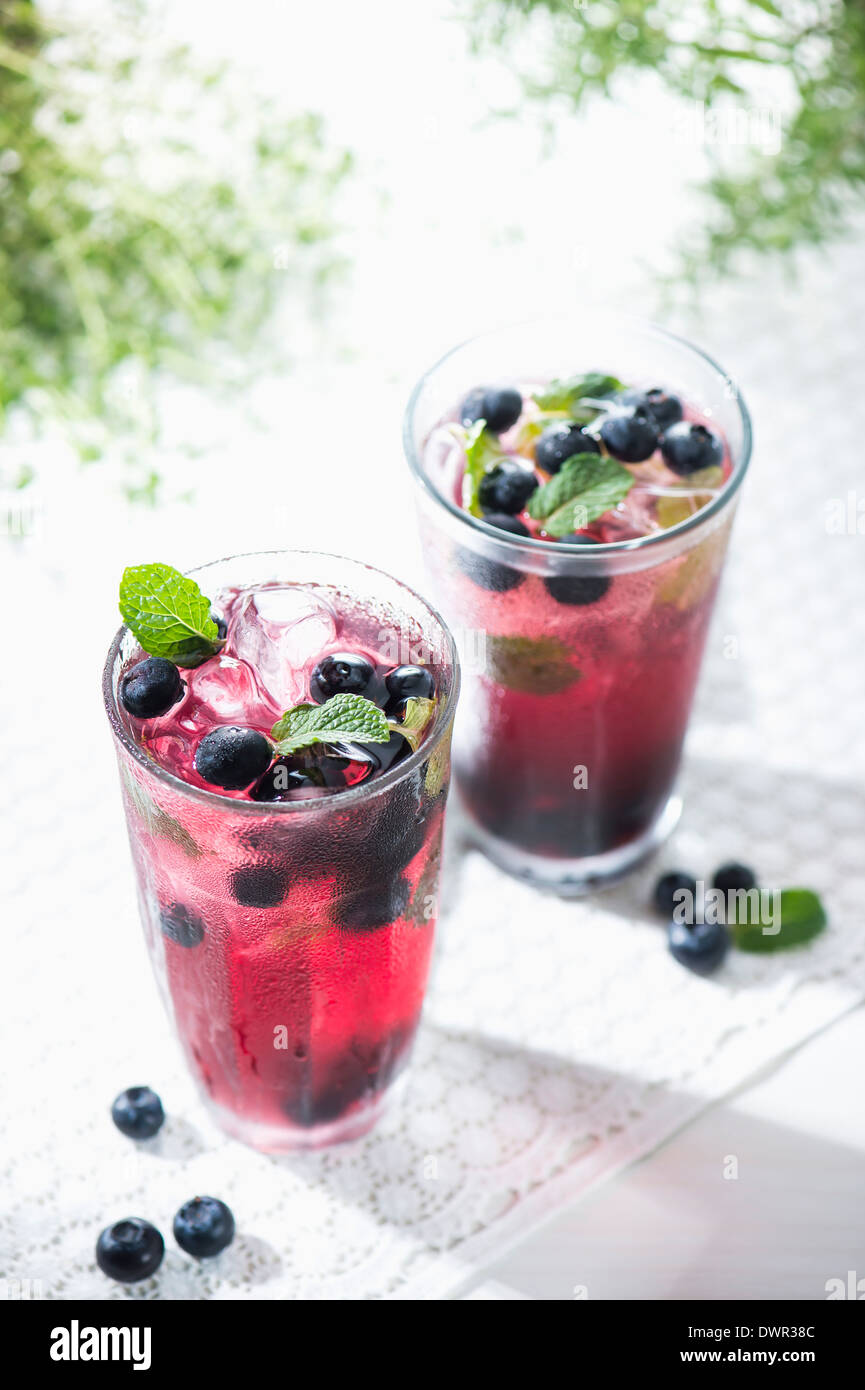 Bicchieri di succo di frutti di bosco con bacche di colore blu Foto Stock