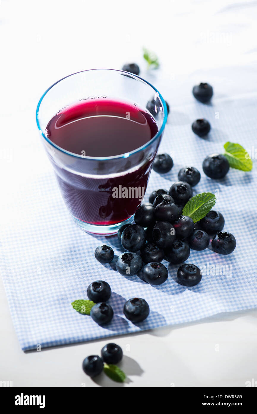 Bicchiere di succo di frutti di bosco con bacche di colore blu Foto Stock