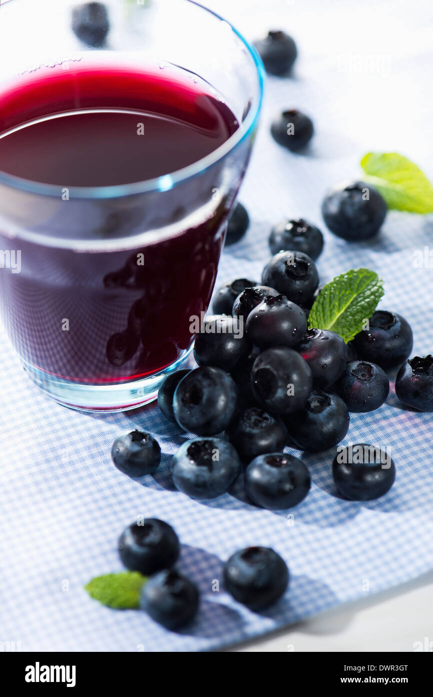 Bicchiere di succo di frutti di bosco con bacche di colore blu Foto Stock