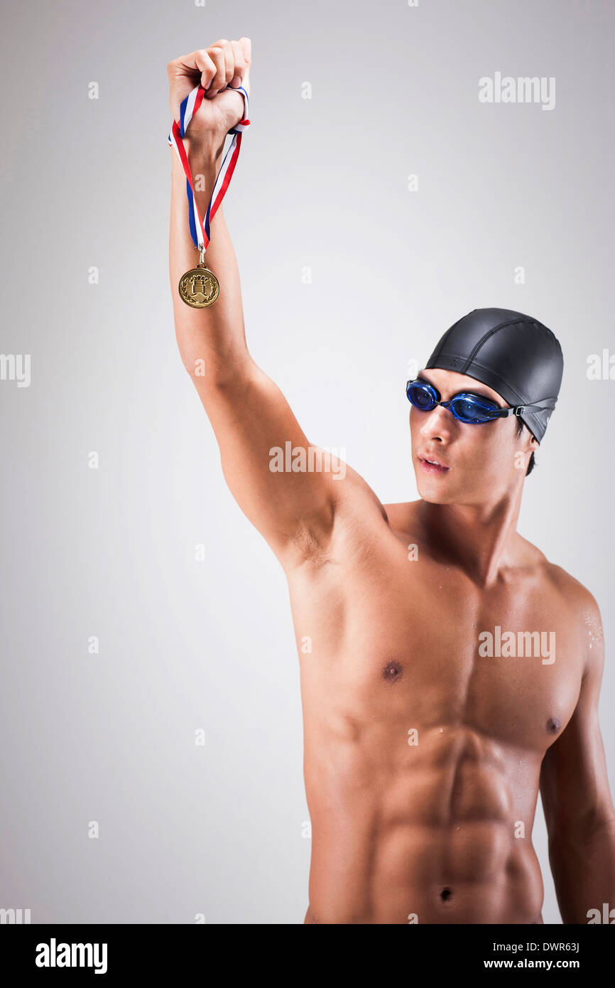 Un uomo con nuoto goggle e hat tenendo una medaglia d oro Foto Stock