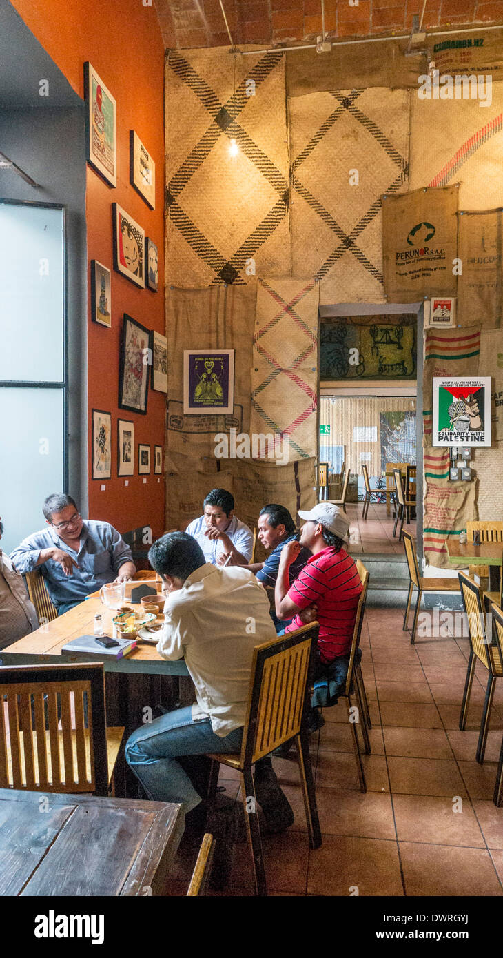 Gruppo messicano di uomini a raccogliere di sinistra cafe con soffitto alto e pareti appeso con caffè saccheggi & poster rivoluzionario di Oaxaca Foto Stock
