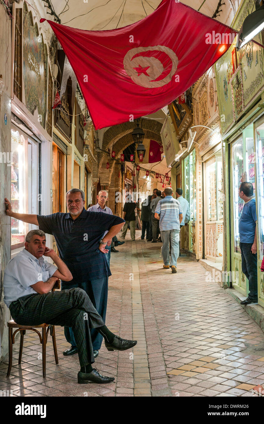 Il Nord Africa, Tunisia, Tunisi. I tenditori uomini sotto bandiera Tunisina in un souk. Foto Stock