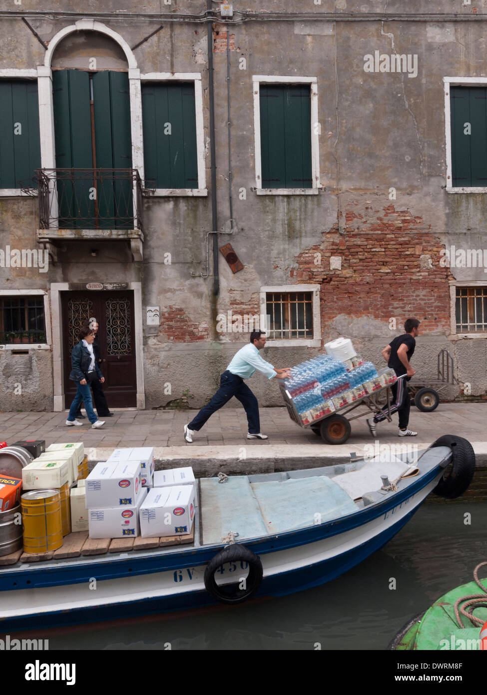 I lavoratori sono lo scarico di una nave cargo che offre cibi di un ristorante nel centro storico di Venezia Foto Stock