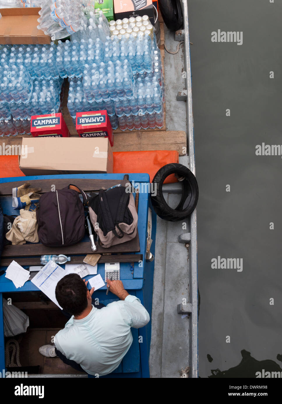 Un deliveryman nella sua barca da carico che offre cibo e bevande per ristoranti a un canale del centro storico di Venezia Foto Stock