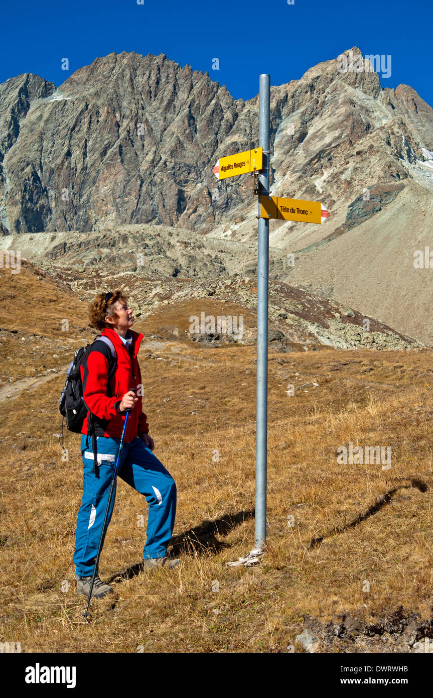 Escursionista presso un segno direzionale di fronte alla catena montuosa Aiguilles Rouges d'Arolla, Arolla, Vallese, Svizzera Foto Stock