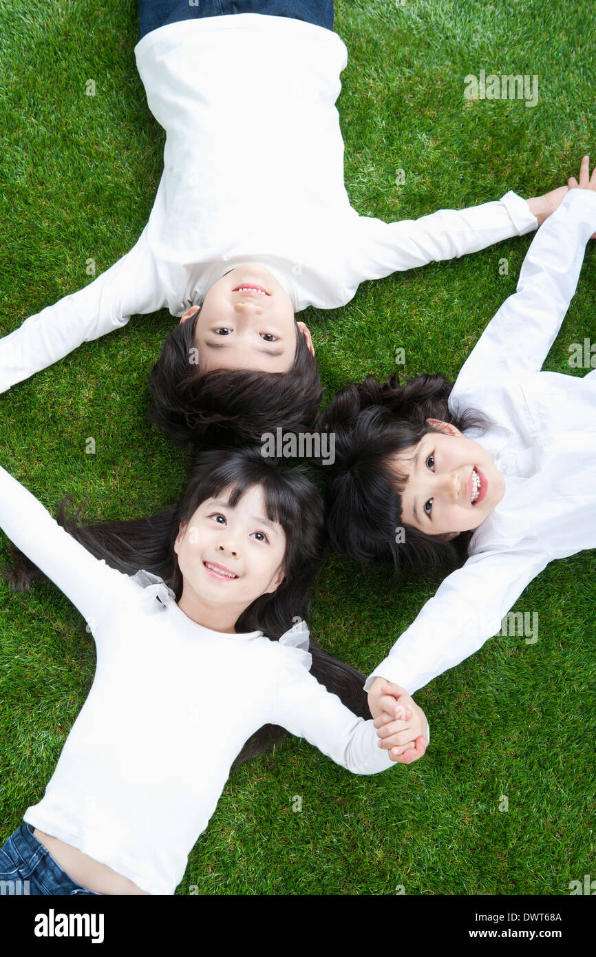 Tre bambini sdraiati sull'erba Foto Stock