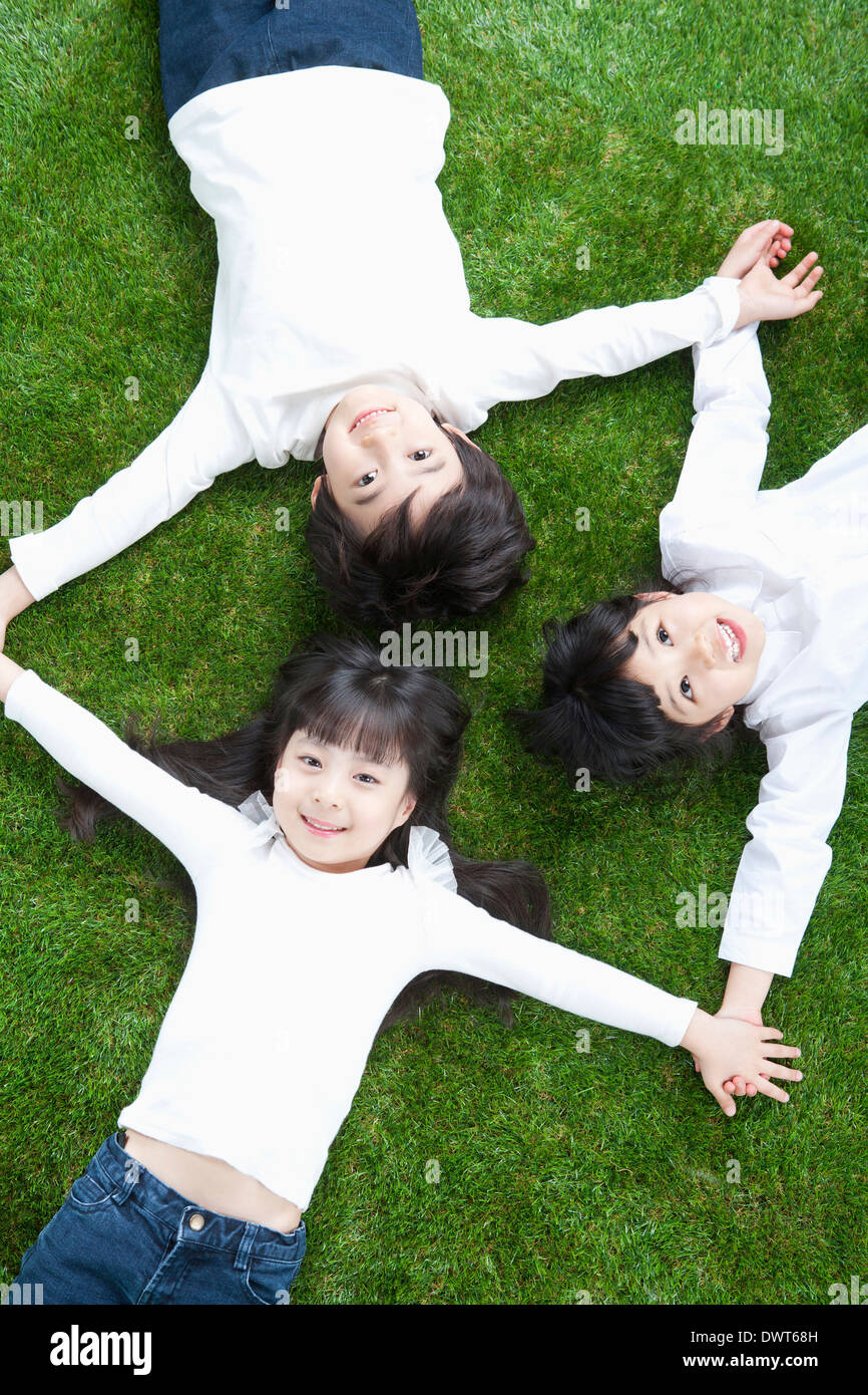 Tre bambini sdraiati sull'erba Foto Stock