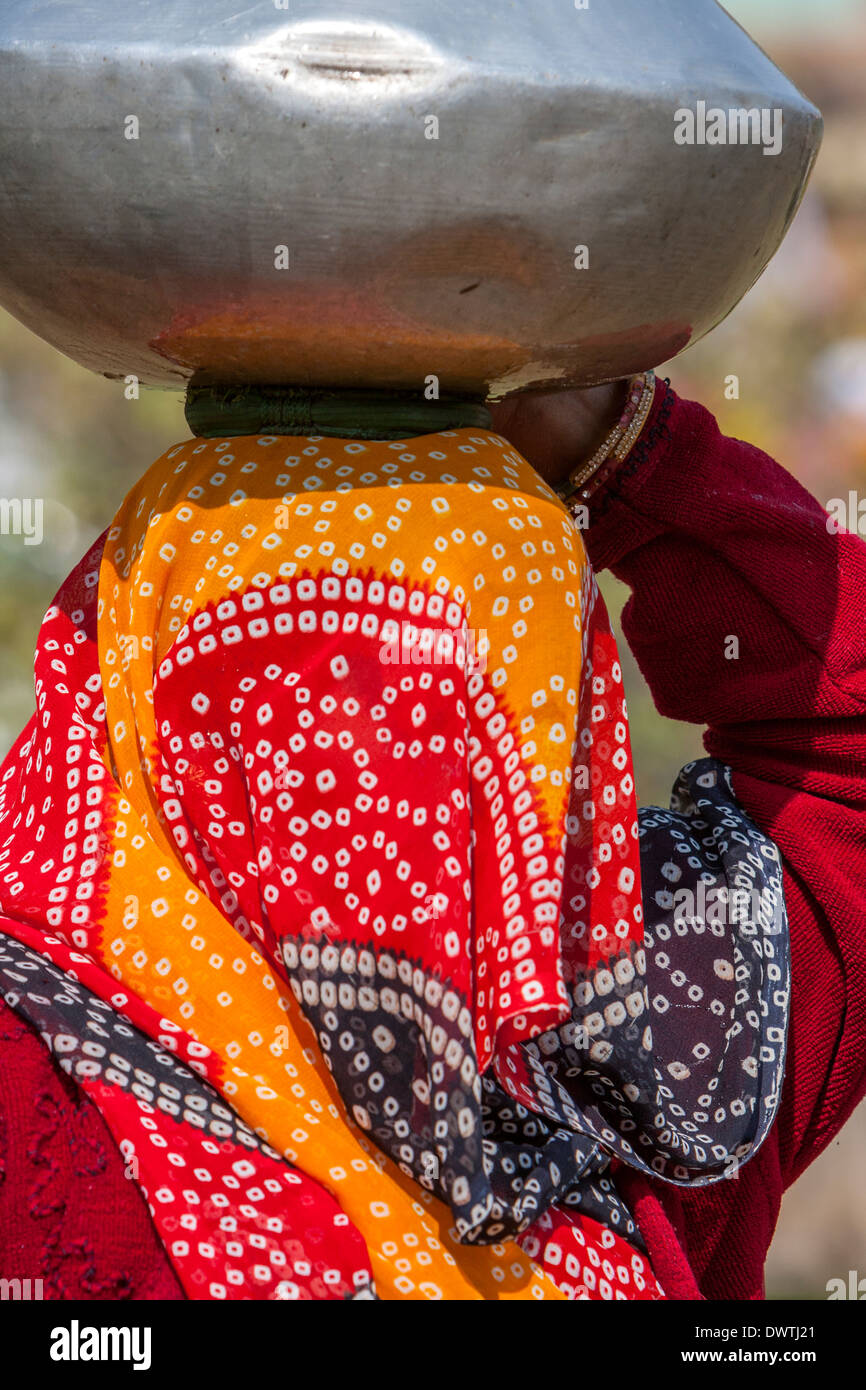 Abhaneri, Rajasthan, India. Pentola di acqua si appoggia su un tampone in fibra sulla parte superiore della testa di un villaggio della donna. Foto Stock