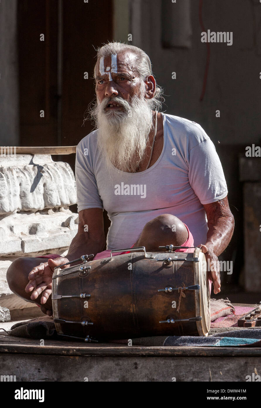 Jaipur, Rajasthan, India. Un Sadhu--religioso indù- ascetico-Riproduzione di un tamburo. Foto Stock