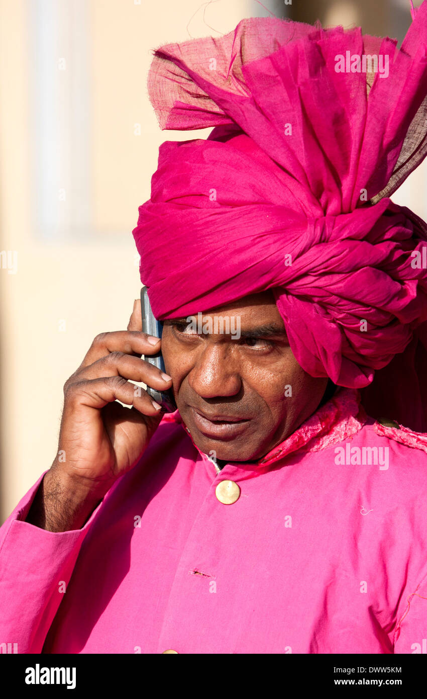 Jaipur, Rajasthan, India. Guardia all entrata del palazzo di città in ascolto per telefono cellulare prima di un ricevimento di nozze. Foto Stock