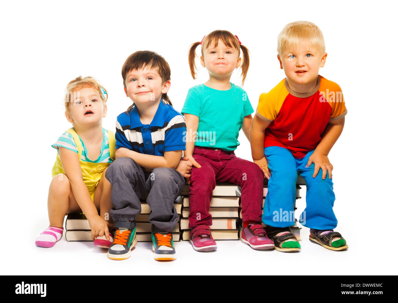 Quattro piccoli bambini seduti sulla pila di libri isolato su bianco Foto Stock