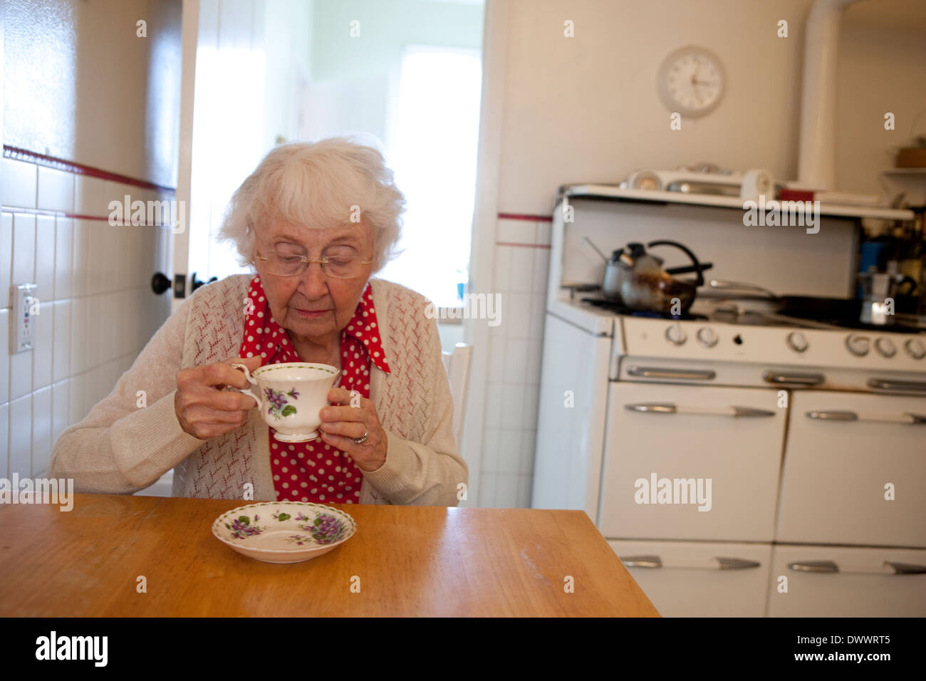 Donna anziana bere il tè in cucina Foto Stock