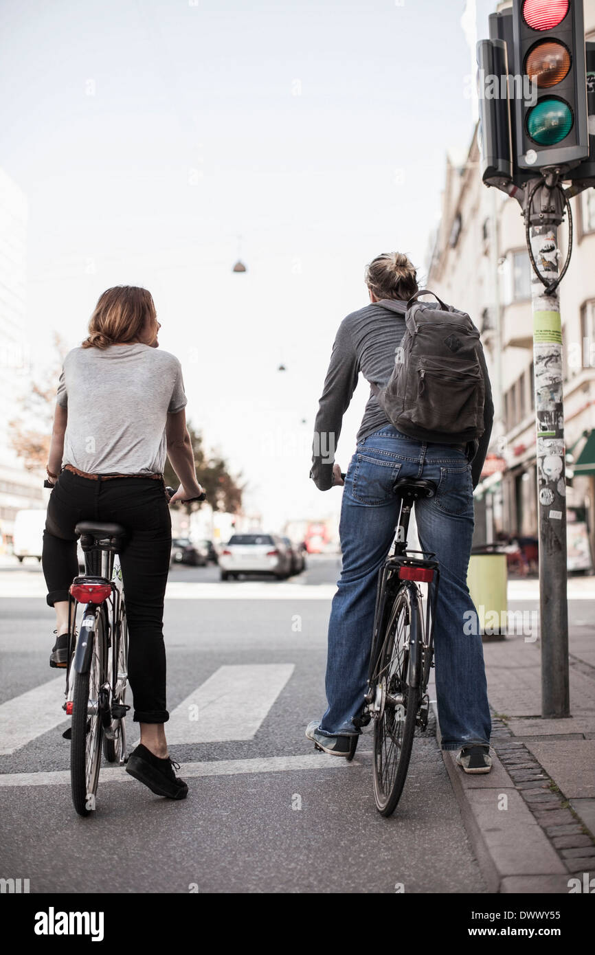 Vista posteriore del giovane con le biciclette in attesa di segnali a via della città Foto Stock
