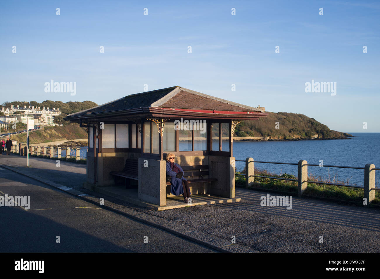Titolare di una pensione o di una rendita si siede in prima serata sole su Cliff Road in Falmouth, Cornwall, Regno Unito Foto Stock