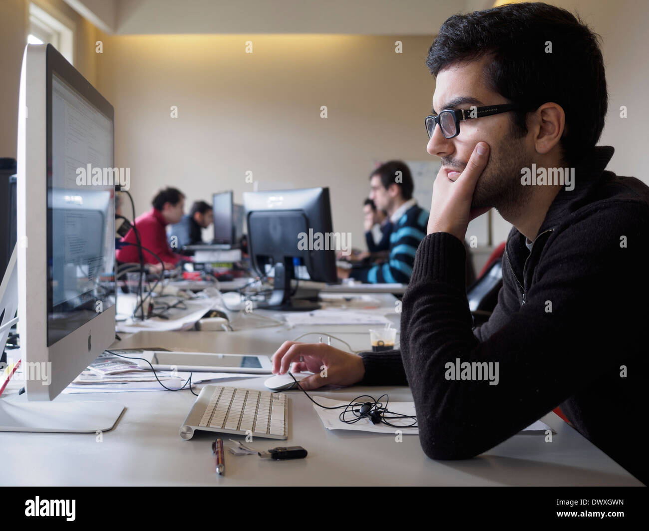 Un uomo che utilizza un computer Apple iMac in uno spazio aperto di Office Foto Stock