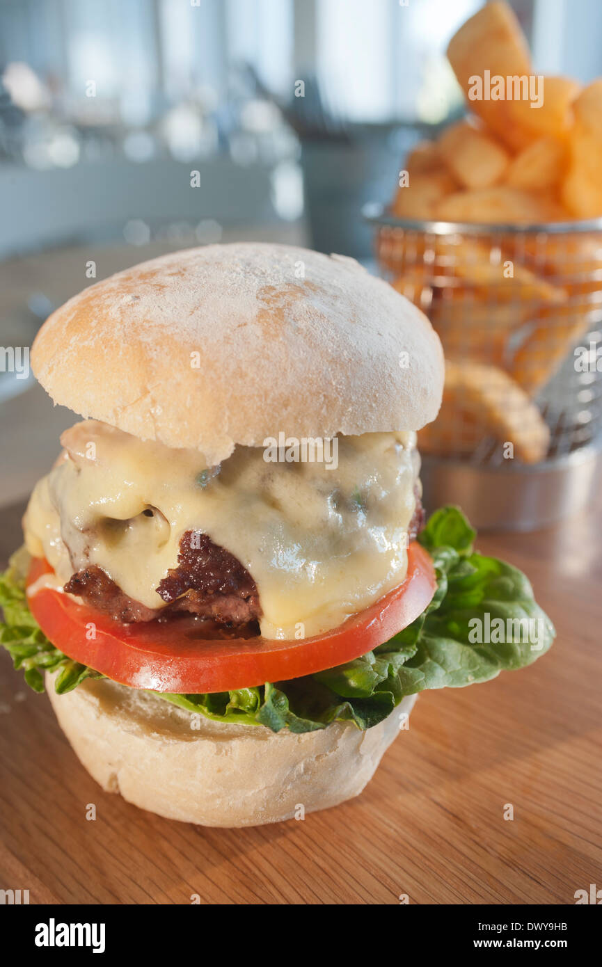 Beefburger classico con insalata, pancetta e formaggio, servita con un ordine di patate fritte o chip. Foto Stock