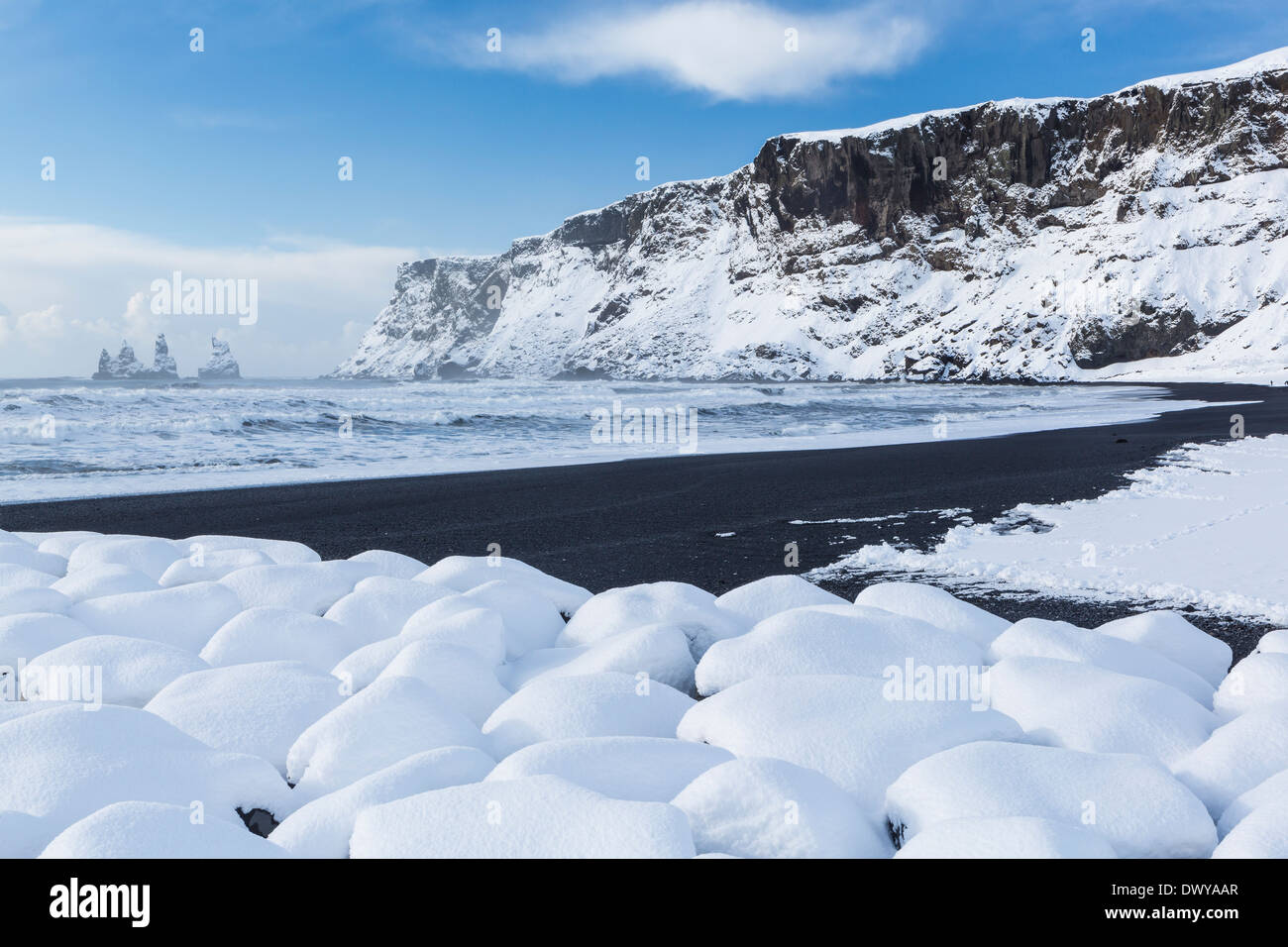 Reynisfjall montagne alte scogliere e pile di mare coperta con caduta di neve fresca a Vík í Mýrdal sulla costa sud dell'Islanda Foto Stock