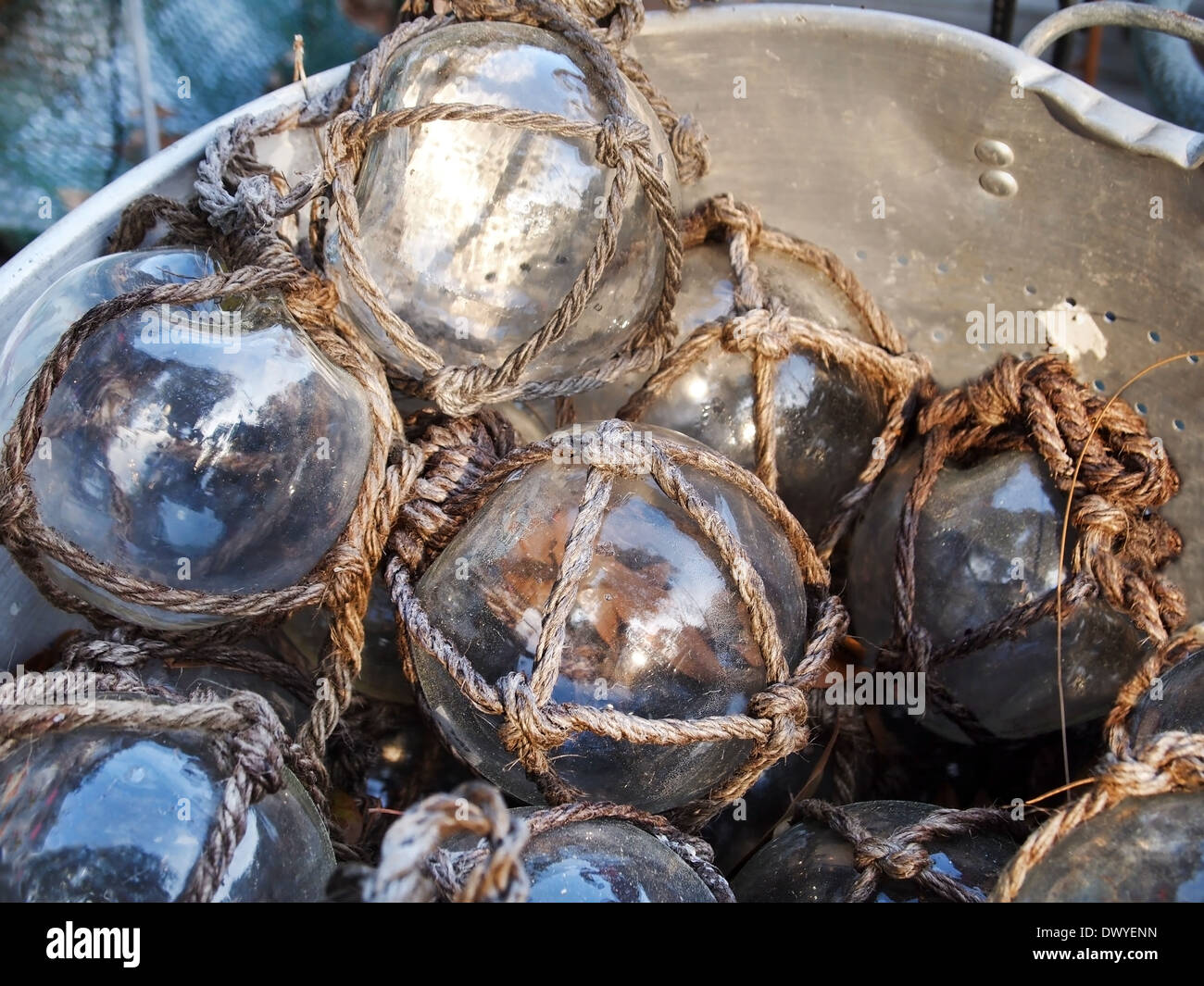 Un grande cucchiaio di metallo riempito di vetro chiaro galleggianti pesca tutti avvolti in corda netting. Foto Stock