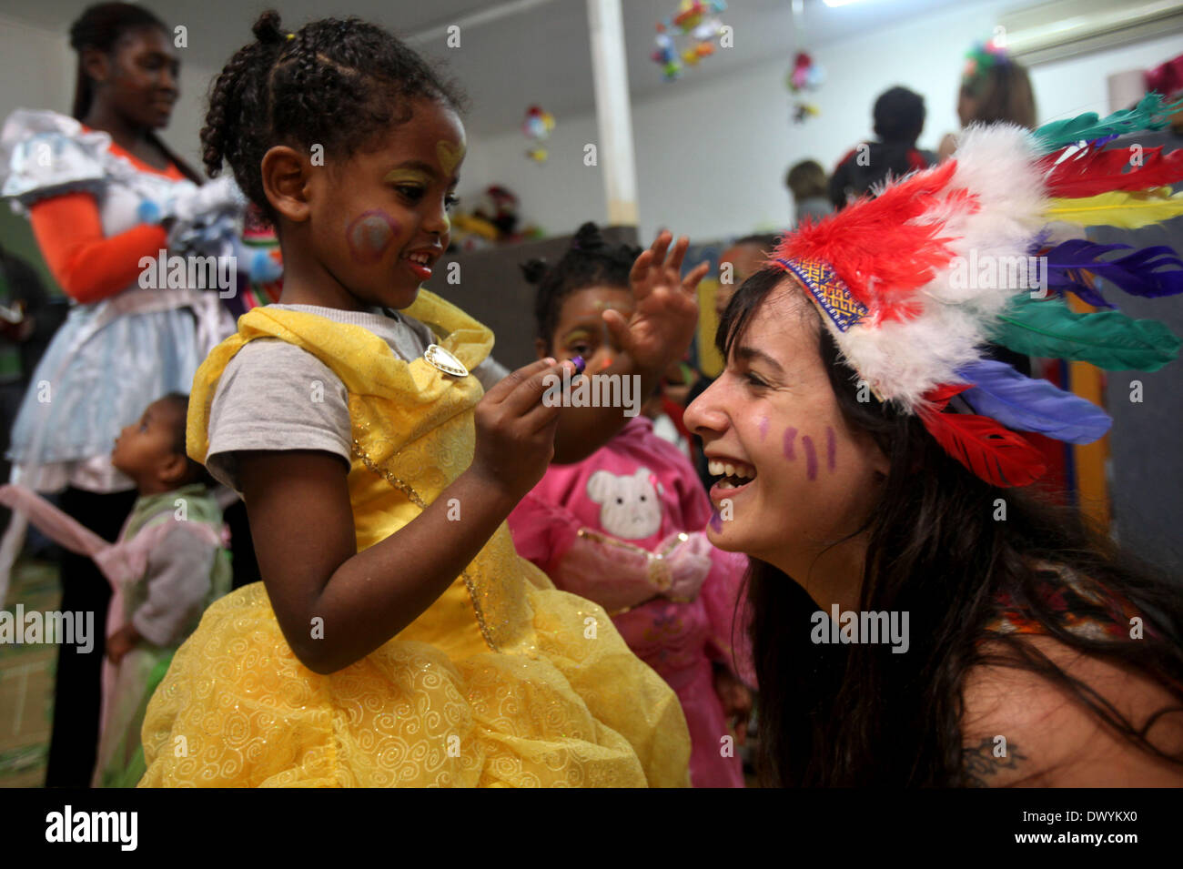 Tel Aviv, Israele. Xiv Mar, 2014. Un israeliano volontario (R) celebra la prossima festa di Purim con bambini di i richiedenti asilo africani in un asilo nido a Tel Aviv, Israele, il 14 marzo 2014. Purim, celebrato quest anno dal tramonto, 15 marzo al calar della sera, 16 marzo è una festa ebraica che commemora la liberazione del popolo ebraico in persiano antico impero in cui un appezzamento è stata formata per distruggerli. © Gil Cohen Magen/Xinhua/Alamy Live News Foto Stock