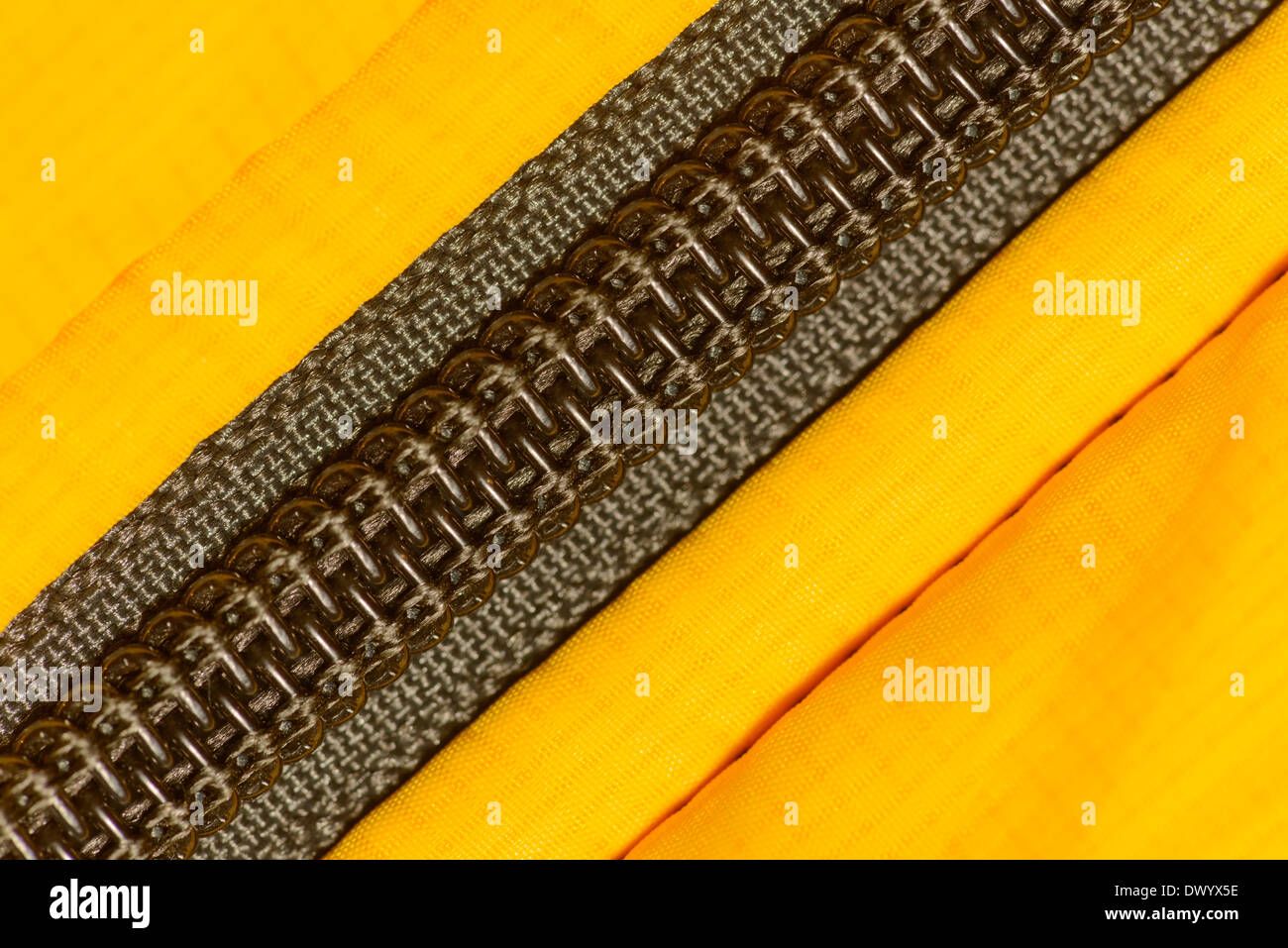 Una bobina di zipper fatta di spirale di elementi in materia plastica cucita in un Giaccone impermeabile giallo. Foto Stock