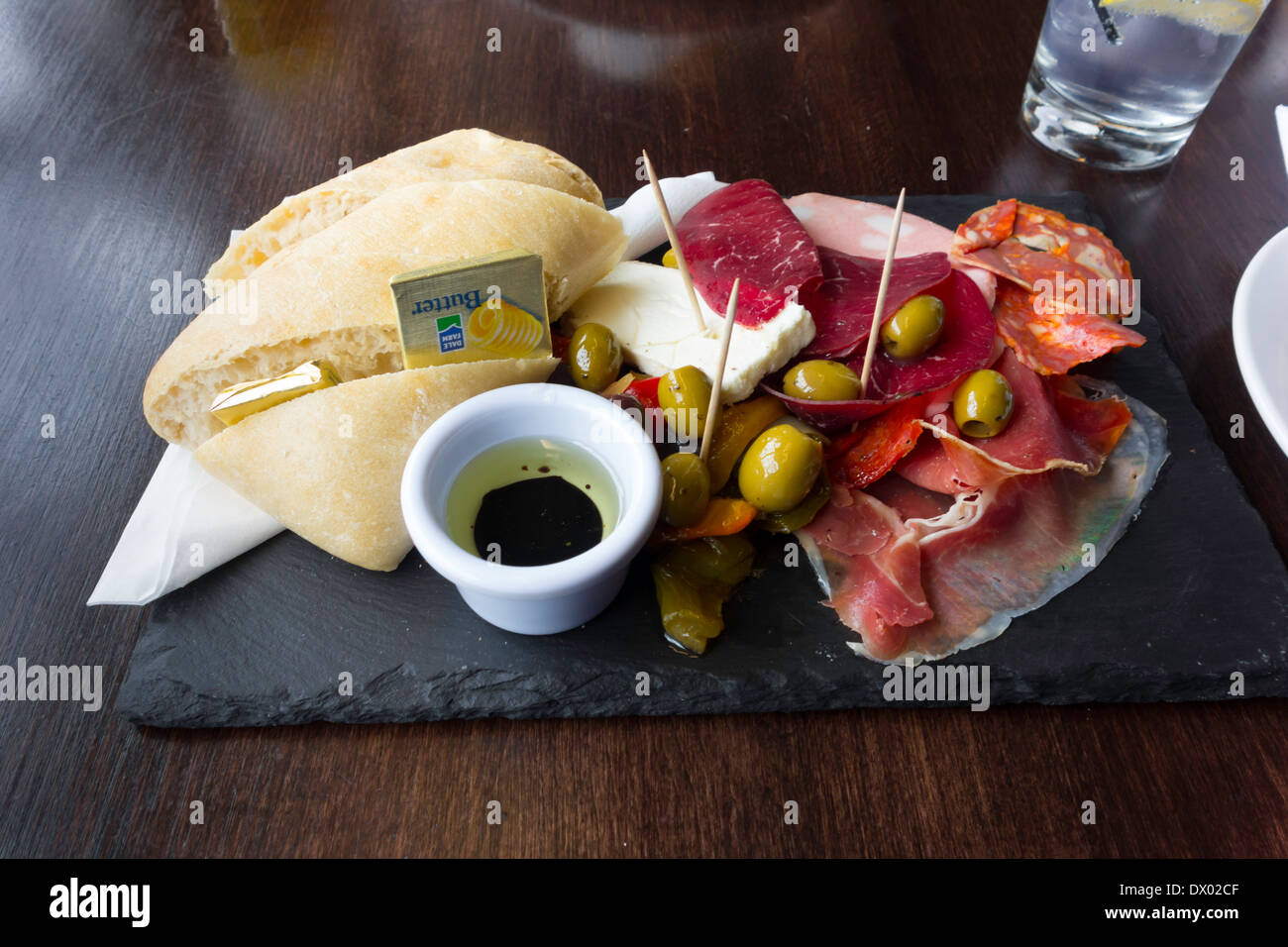 Ora di pranzo snack pasto deli piatto di salumi mozzarella Ciabatta pane olio di oliva olive in salamoia peperoni Foto Stock