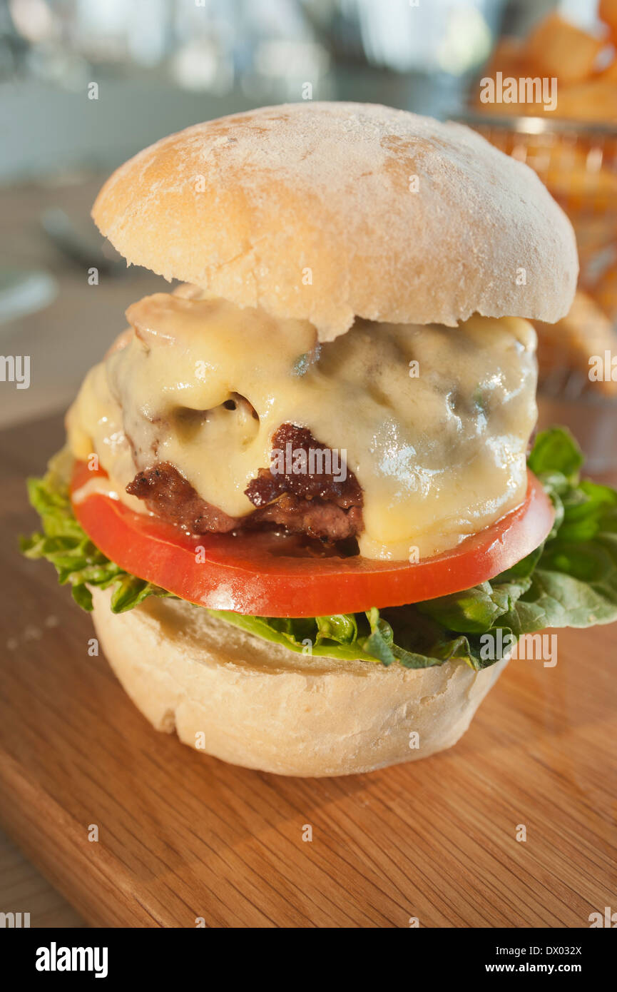 Cheeseburger con pancetta e insalata su di un piatto di legno. Foto Stock