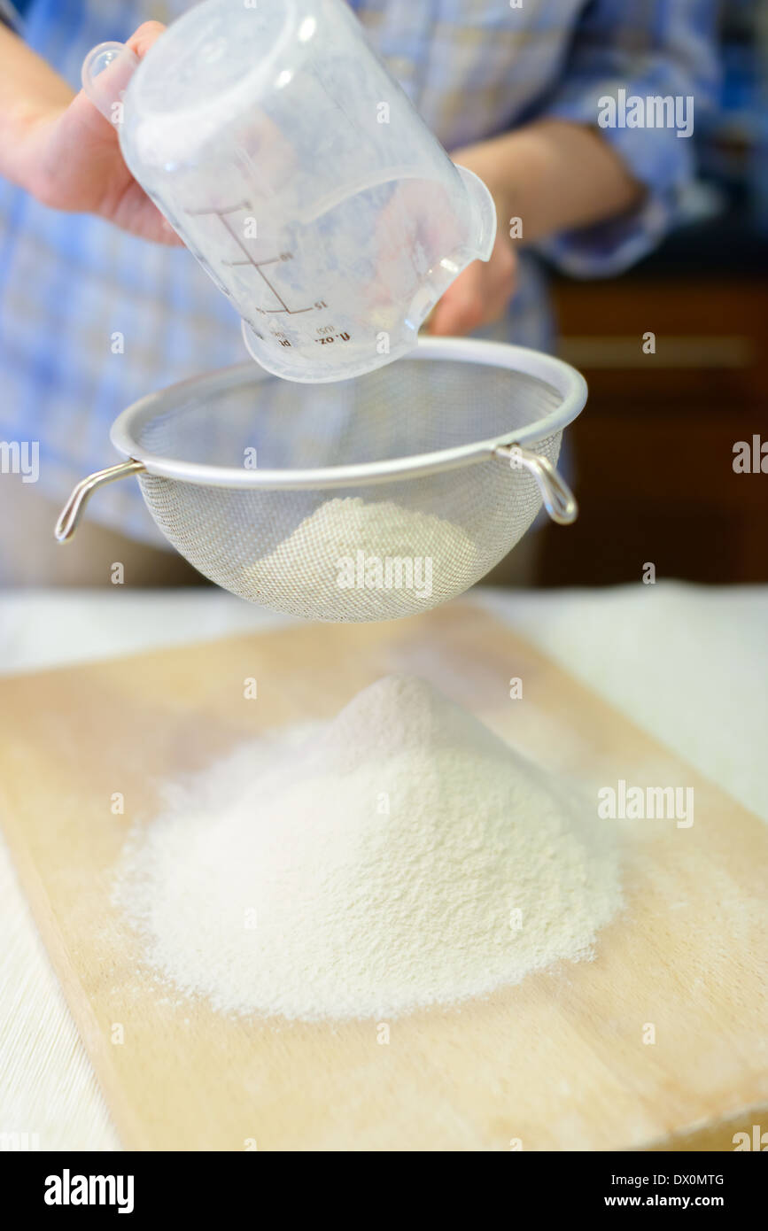 Cucina: donna di setacciare la farina con il crivello inferiore Foto Stock