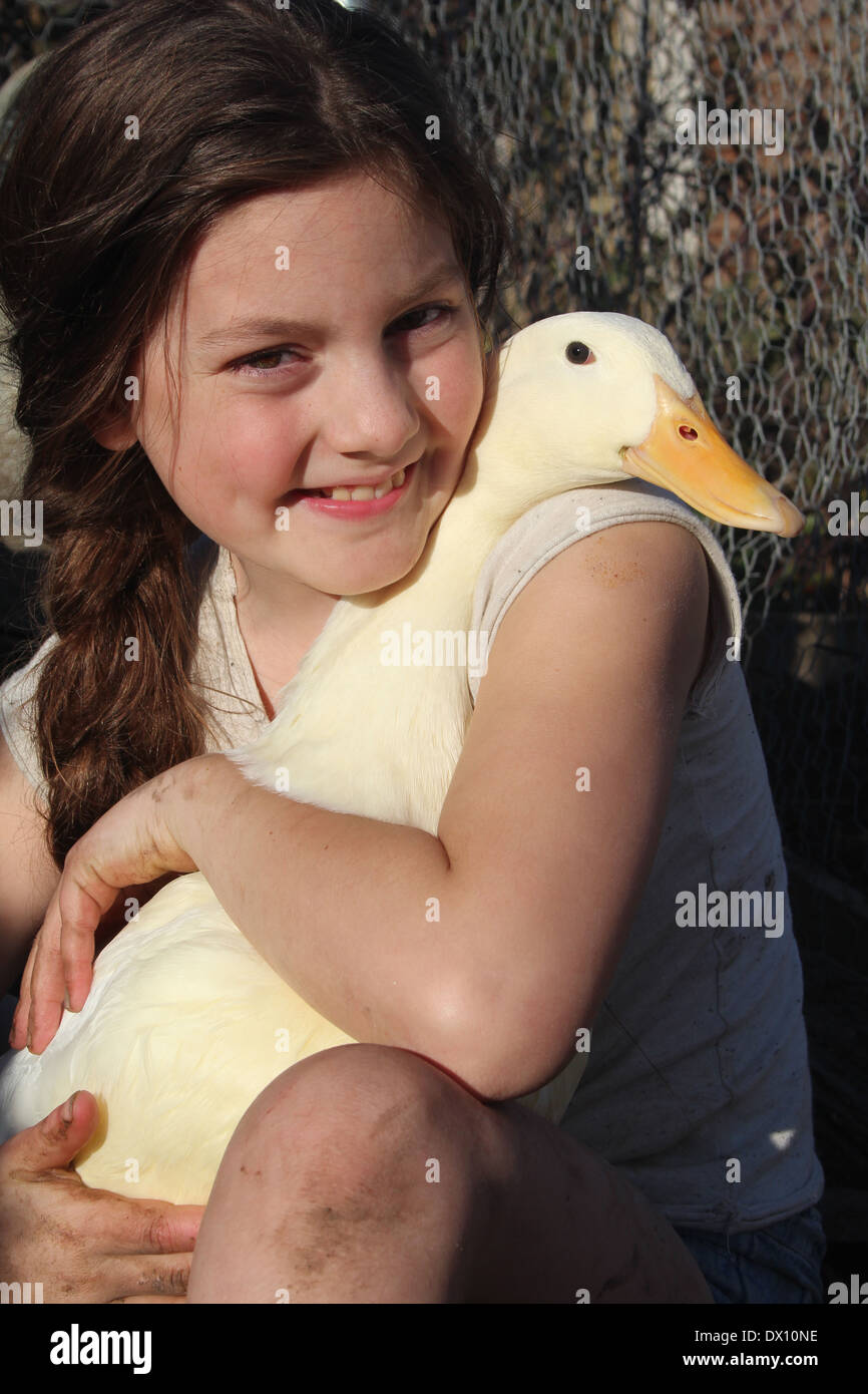 Giovane ragazza caucasica abbracciando il suo tame pet pekin anatra (Anas platyrhynchos) e suo pekin duck abbracciando il suo indietro, UK, Inghilterra Foto Stock