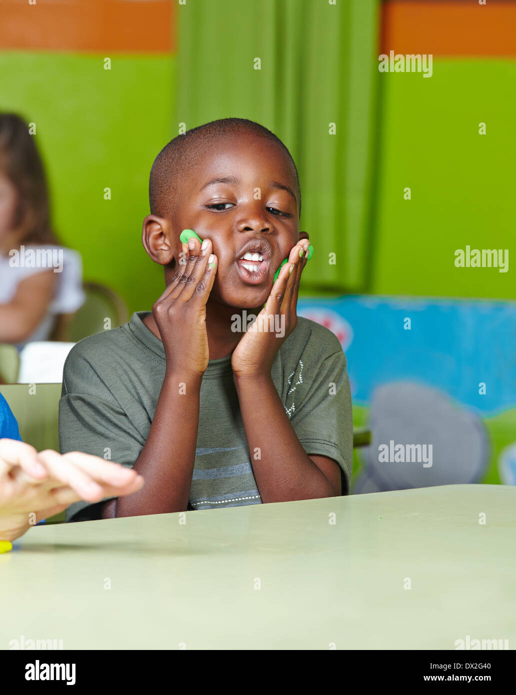 Silly bambino africano fare stupidaggini con impasto in un kindergarten Foto Stock