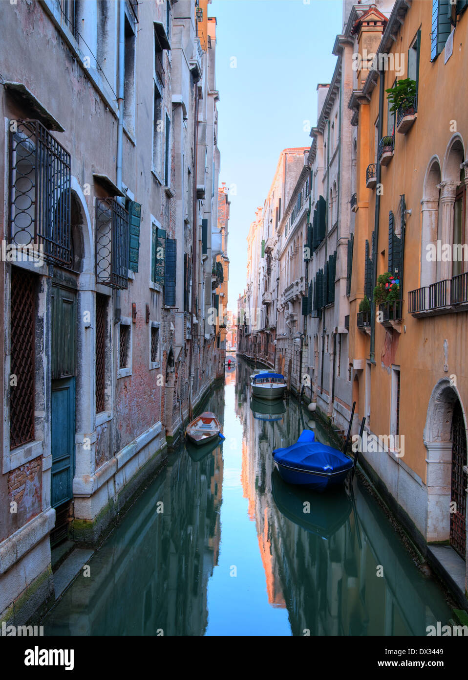 Stretto canale di Venezia con alcune barche all'alba Foto Stock