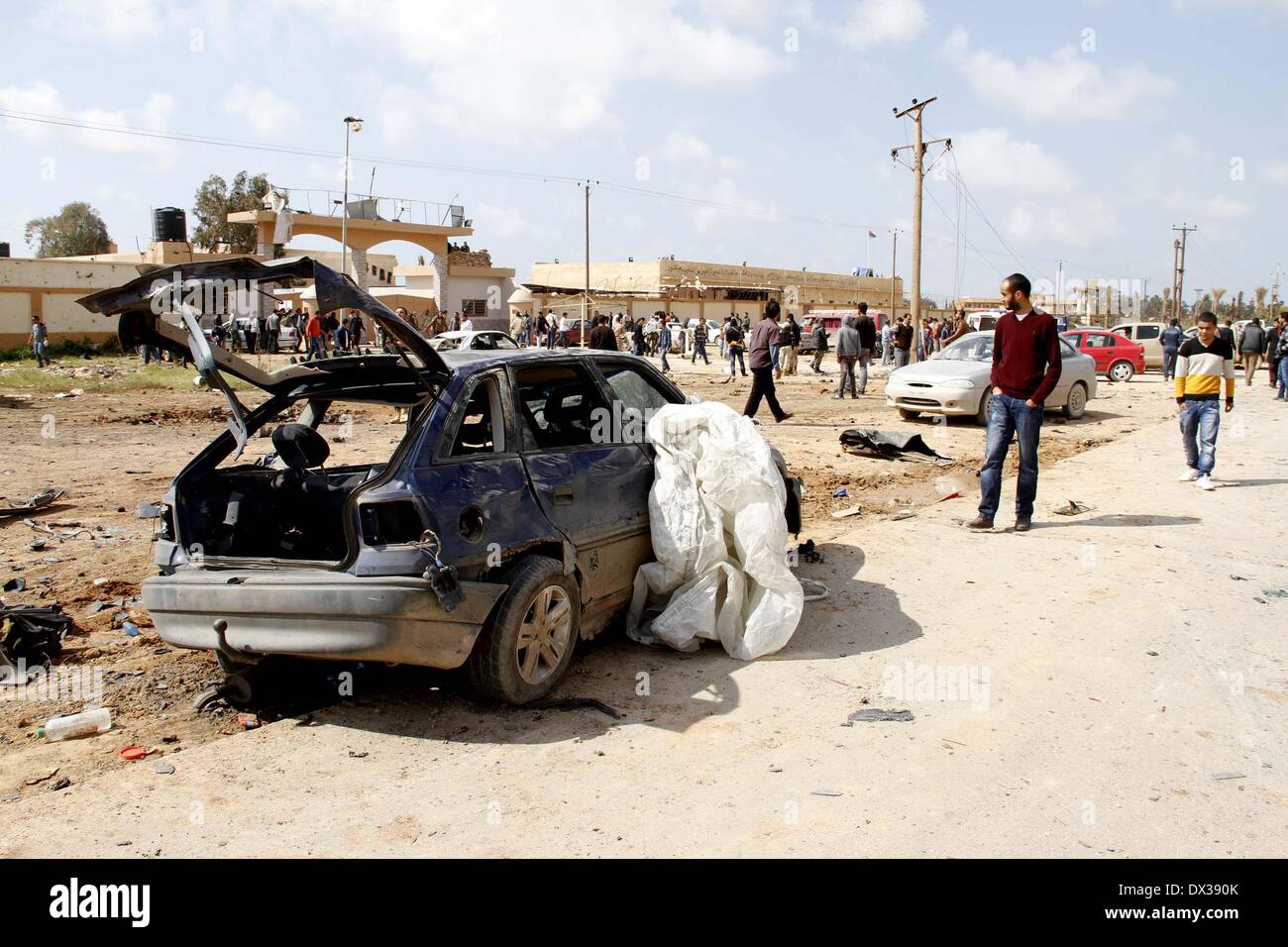 Bengasi, Libia. Xvii Mar, 2014. Persone controllare la vettura danneggiata a Bengasi, Libia, Marzo 17, 2014. Un auto bomba di targeting un militare libico camp a Bengasi ha ucciso almeno cinque soldati feriti e dieci altri lunedì, militare e medico fonti Xinhua ha detto. Credito: Mohammed Elshaiky/Xinhua/Alamy Live News Foto Stock