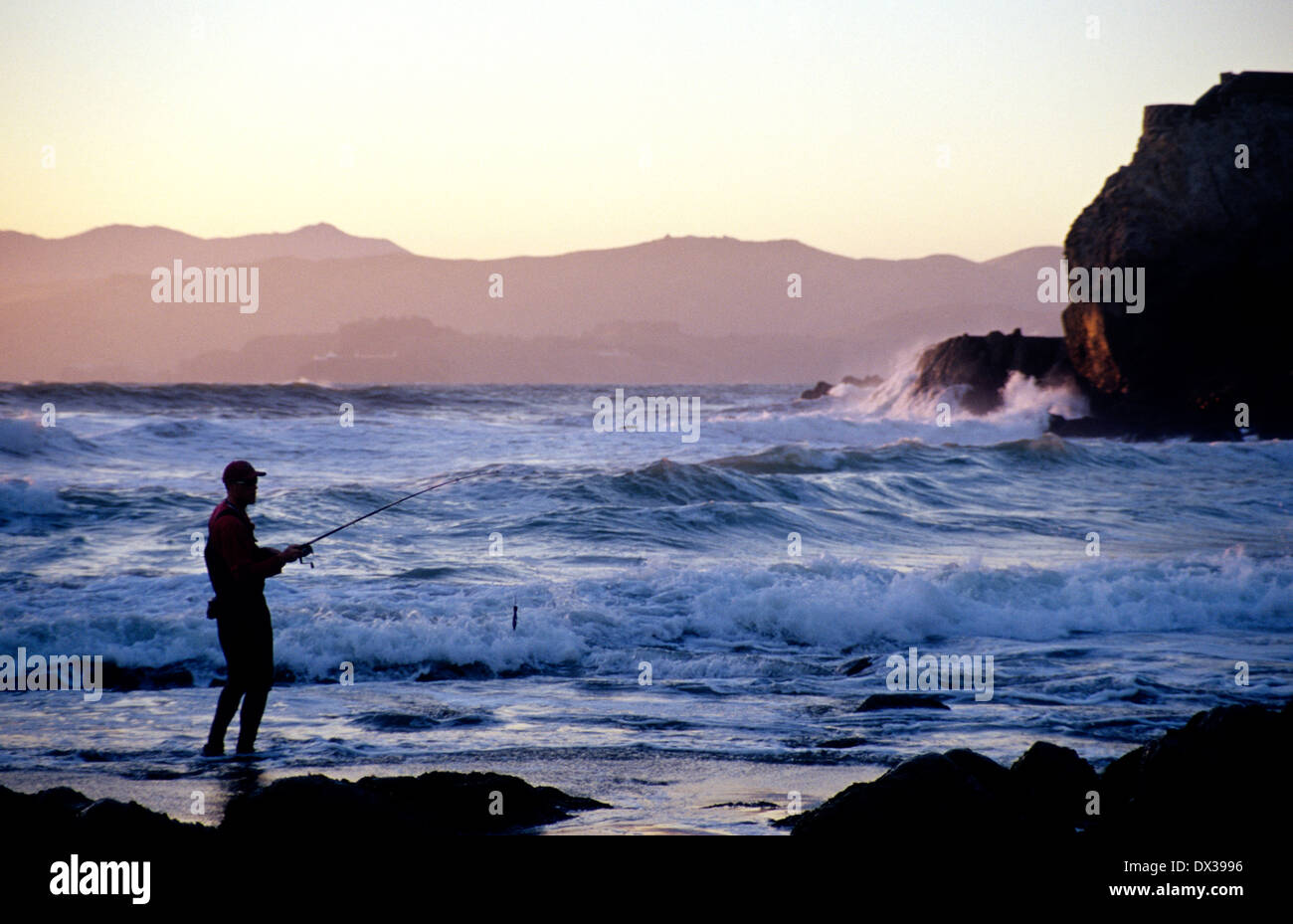 Pescatore pesci per rigatori sotto la scogliera casa sull'oceano Pacifico in San Francisco Foto Stock