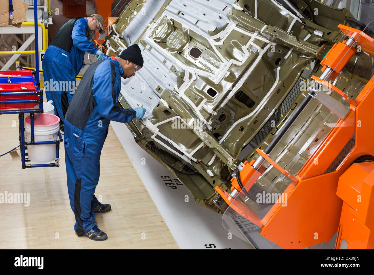 Lavoratori nella tenuta sottoscocca sottoscocca e una stazione di rivestimento del Paint shop a Chrysler's Sterling Heights impianto di assemblaggio. Foto Stock