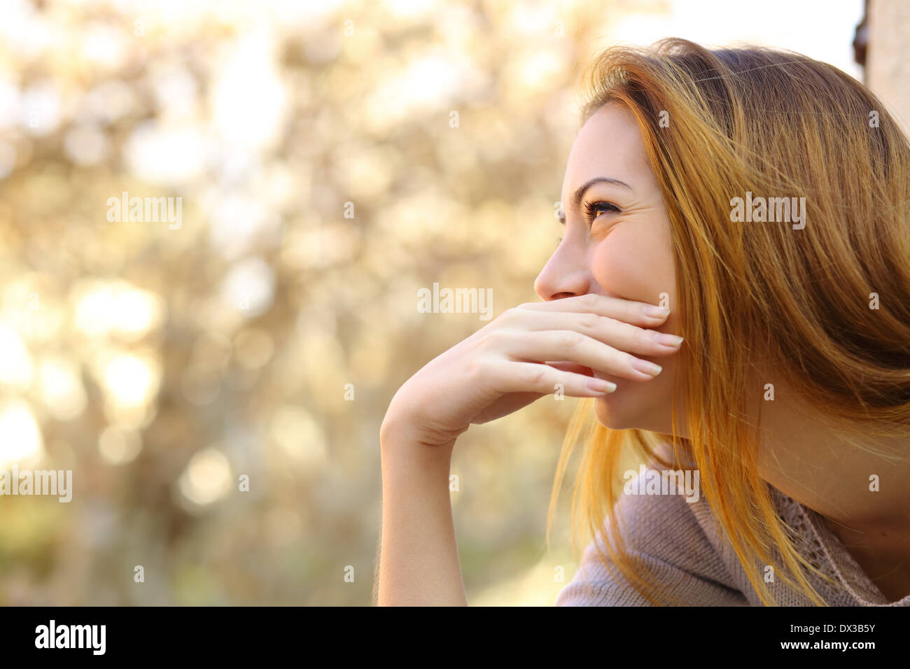 Donna felice ridendo che copre la bocca con una mano con un background di calore Foto Stock