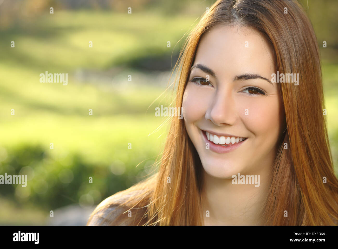 Ritratto di una donna white smile dental care in un parco con un calore verde sullo sfondo Foto Stock