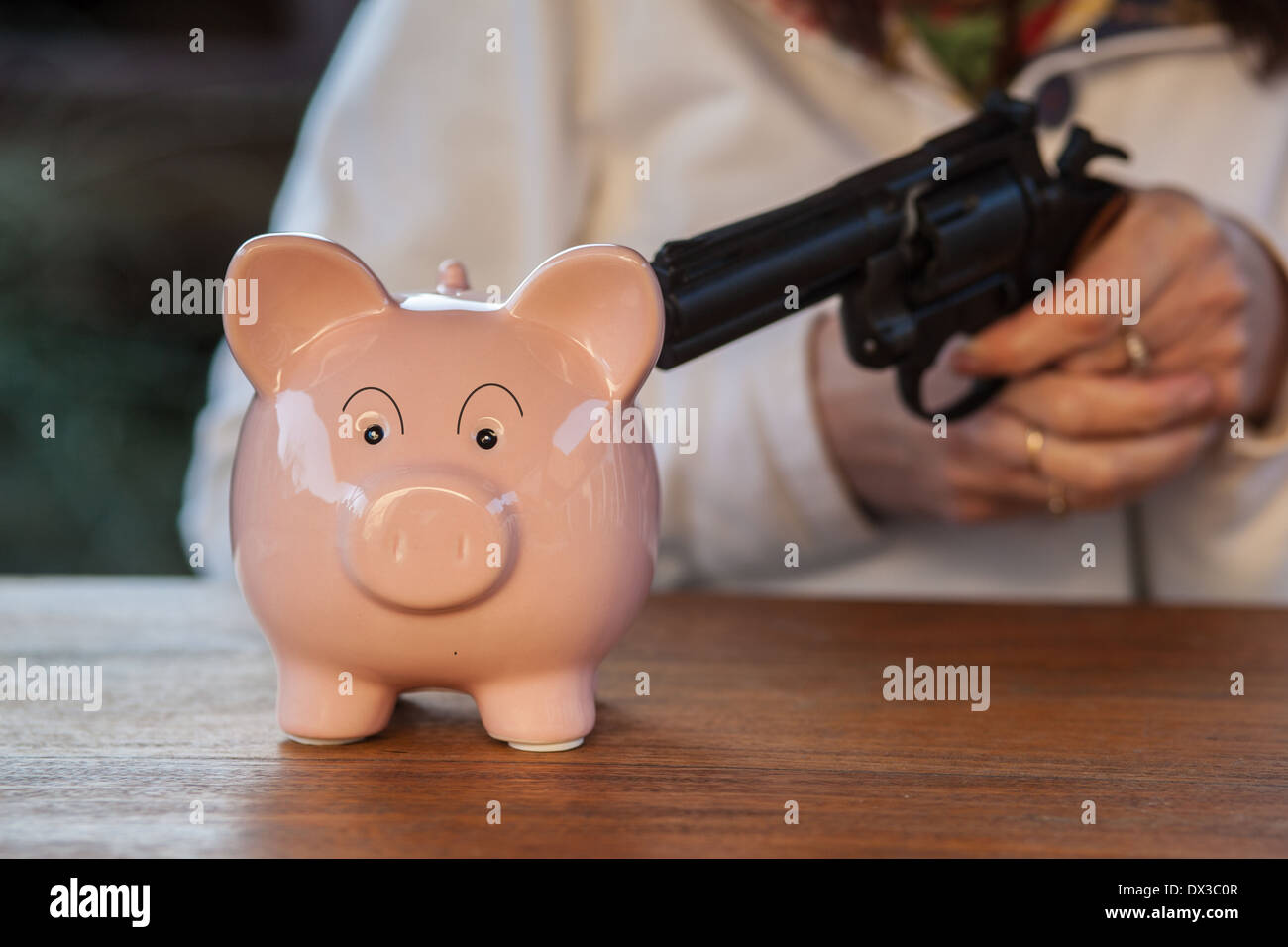 Cina rosa salvadanaio minacciato con una pistola Foto Stock