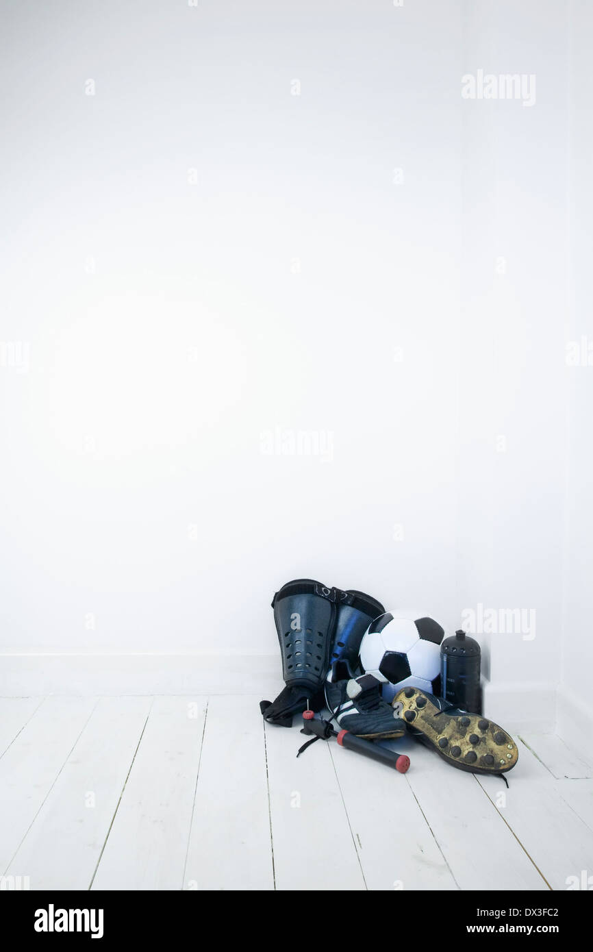 Equipaggiamento di calcio, stivali,parastinchi,football,una bottiglia d'acqua e la pompa a ricircolo di sfere in un angolo di una stanza vuota Foto Stock