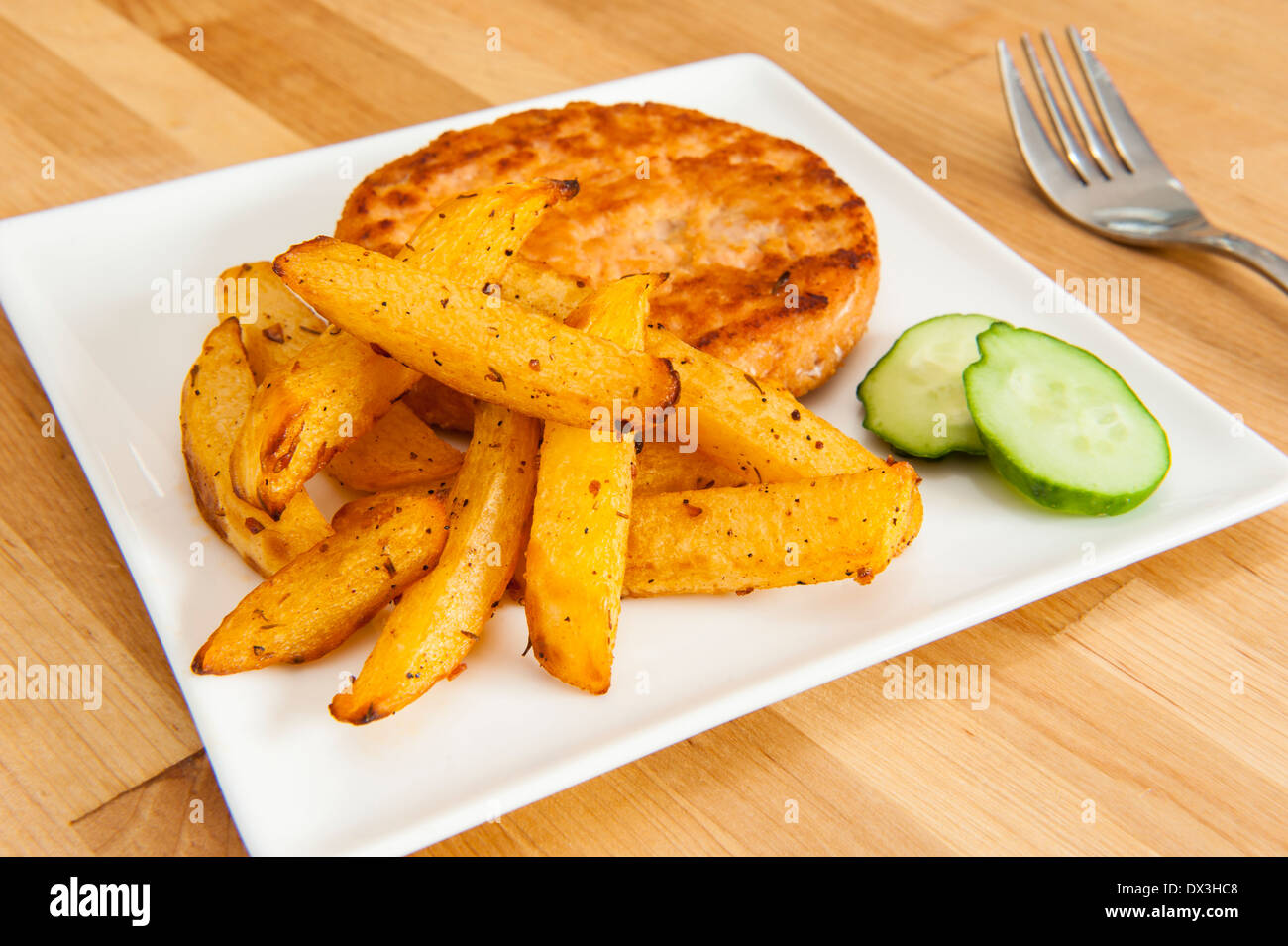 Hamburger di salmone con rutabaga patatine fritte e cetrioli Foto Stock