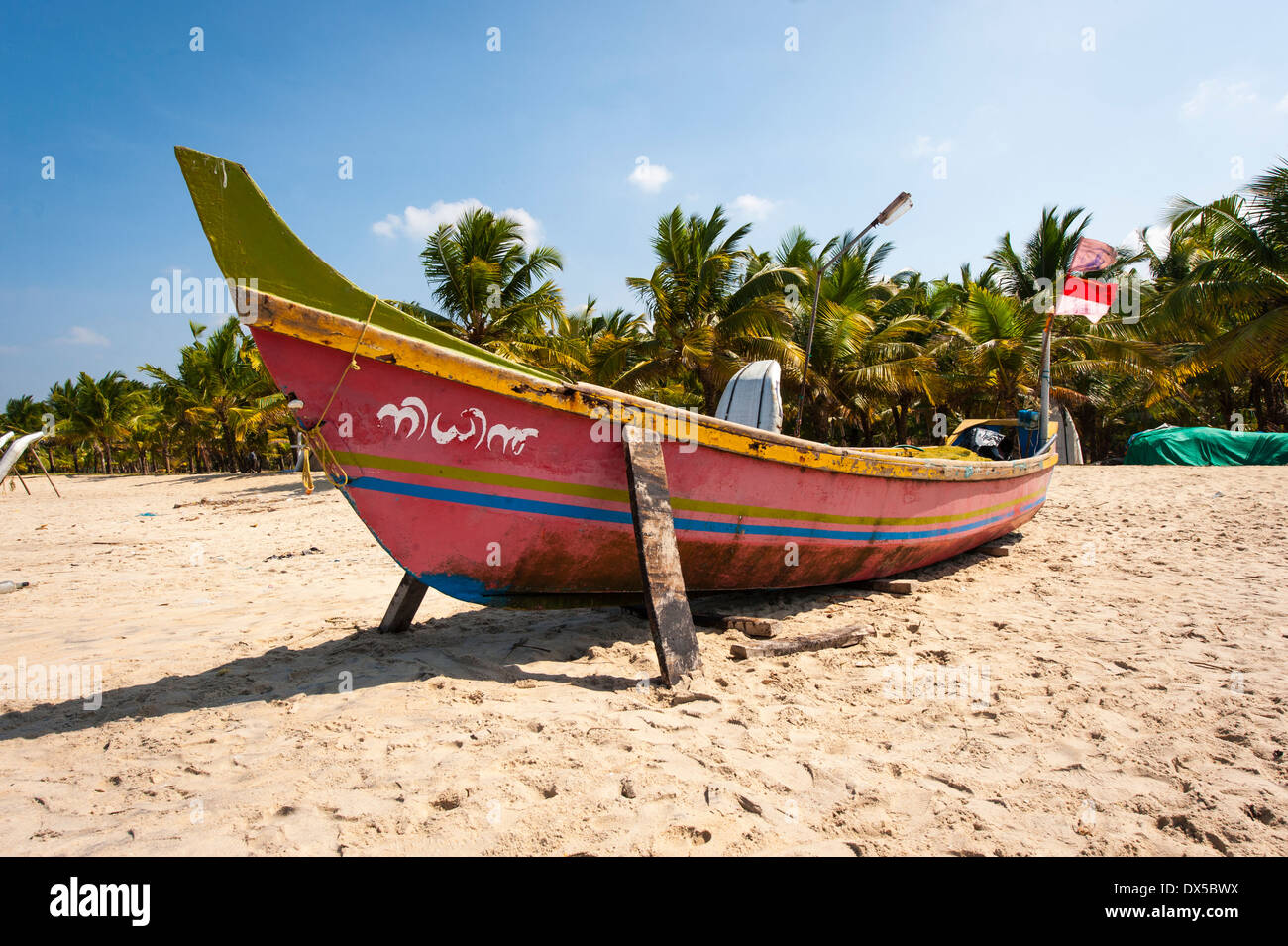 Sud Sud dell India Kerala Alleppy Mararikulam spiaggia barca da pesca in legno sabbia shore sun blue sky scena scenario bandiere alfieri Foto Stock