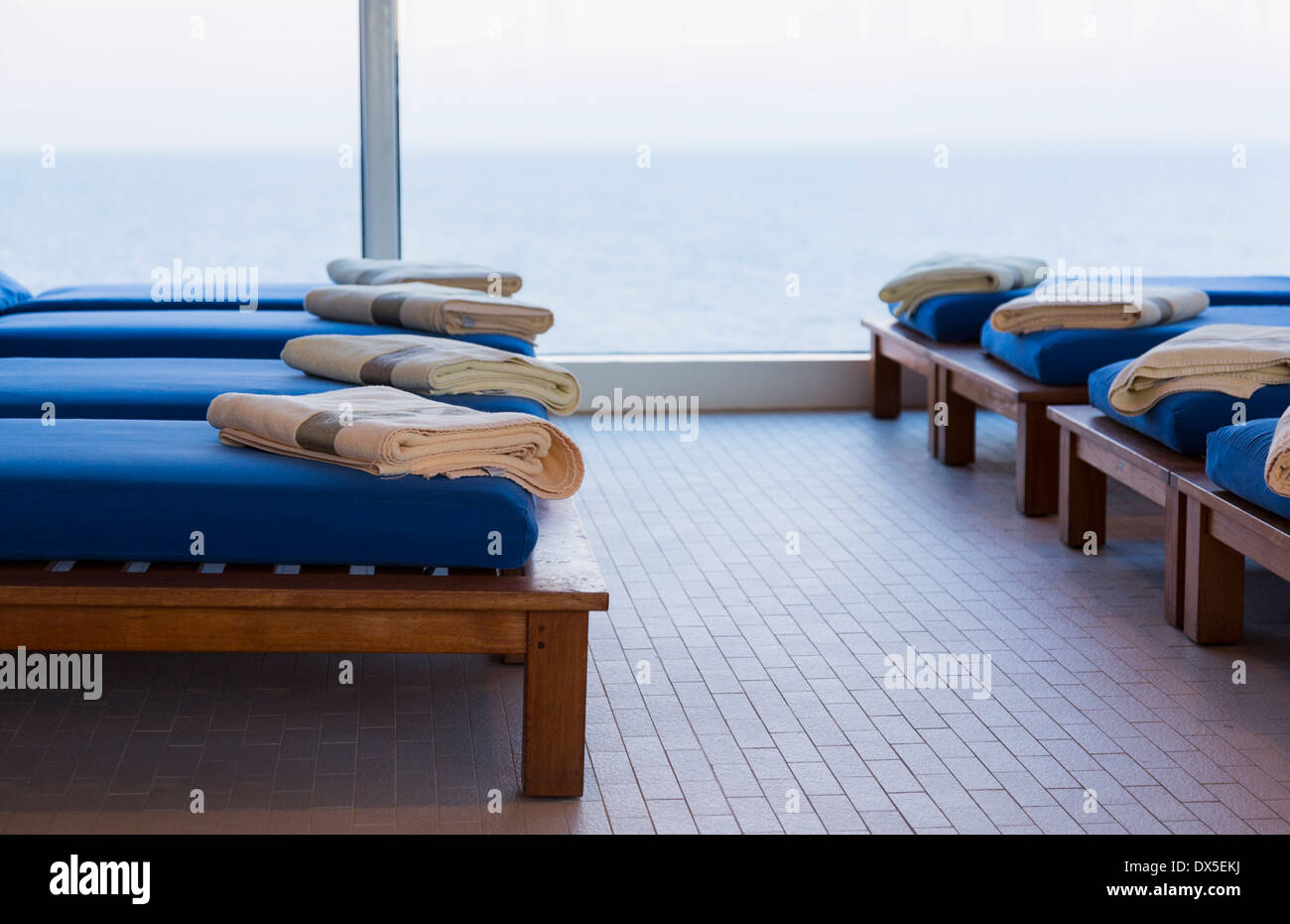 Fila di panche reclinabili in una spa su una nave da crociera da una finestra che guarda al mare Foto Stock
