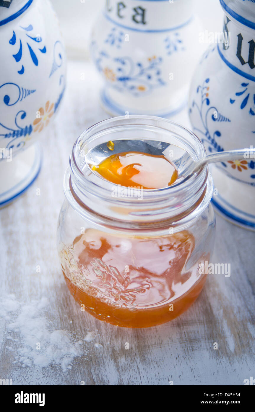 Confettura di albicocche in un vasetto di vetro con contenitori da cucina Foto Stock