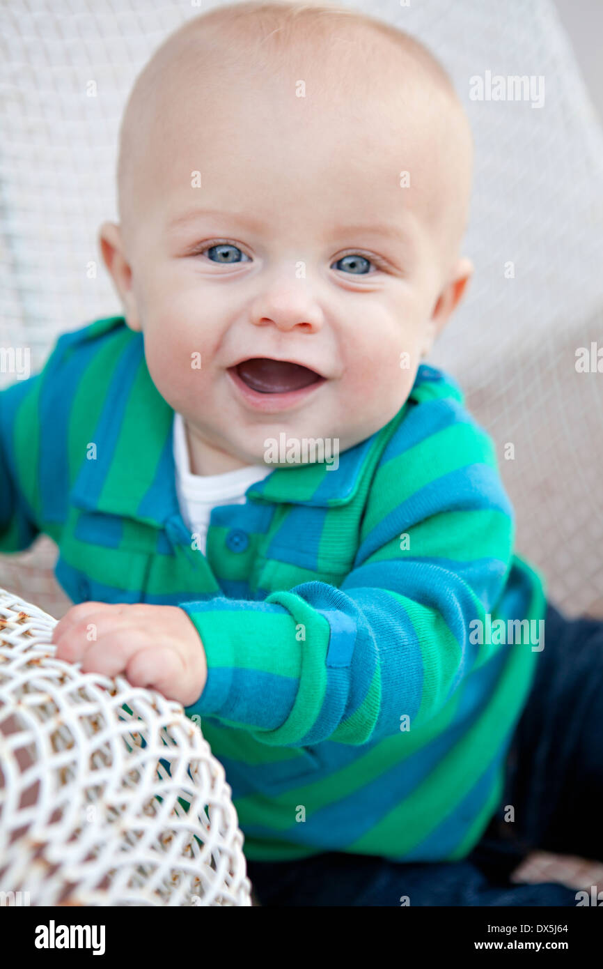 Happy baby boy con la bocca aperta nel filo sedia, ritratto, close up Foto Stock