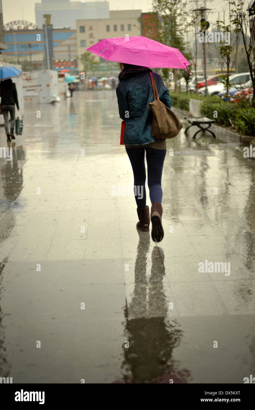Ragazza camminare sotto la pioggia con un ombrello rosa Foto stock - Alamy