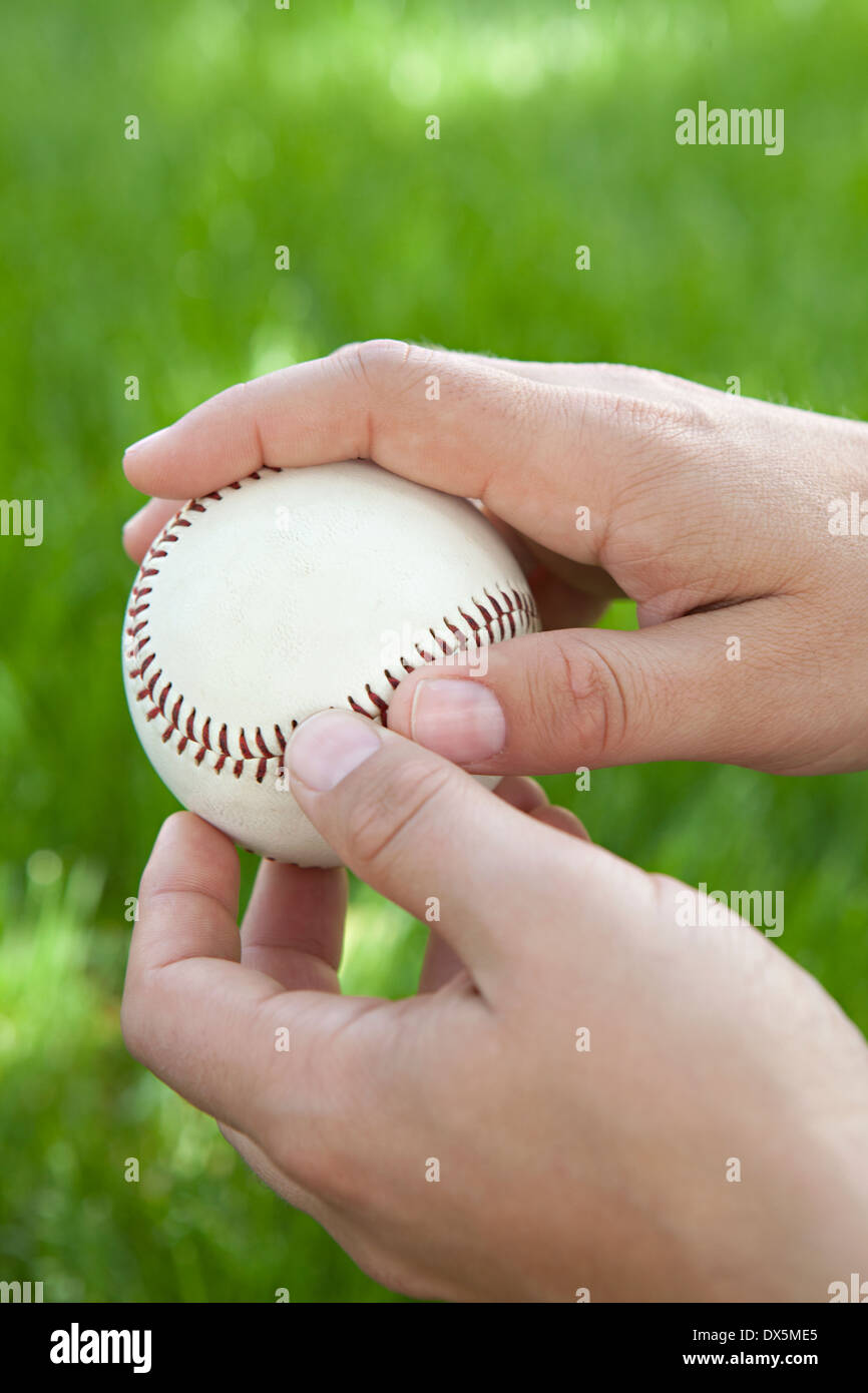 Uomo di mani tenendo il baseball in erba, close up Foto Stock