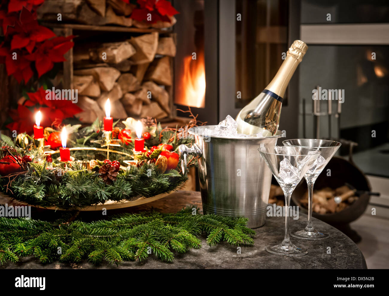Home festosa decorazione di interni per il Natale e il nuovo anno con una bottiglia di champagne e un camino. Cena a lume di candela Foto Stock