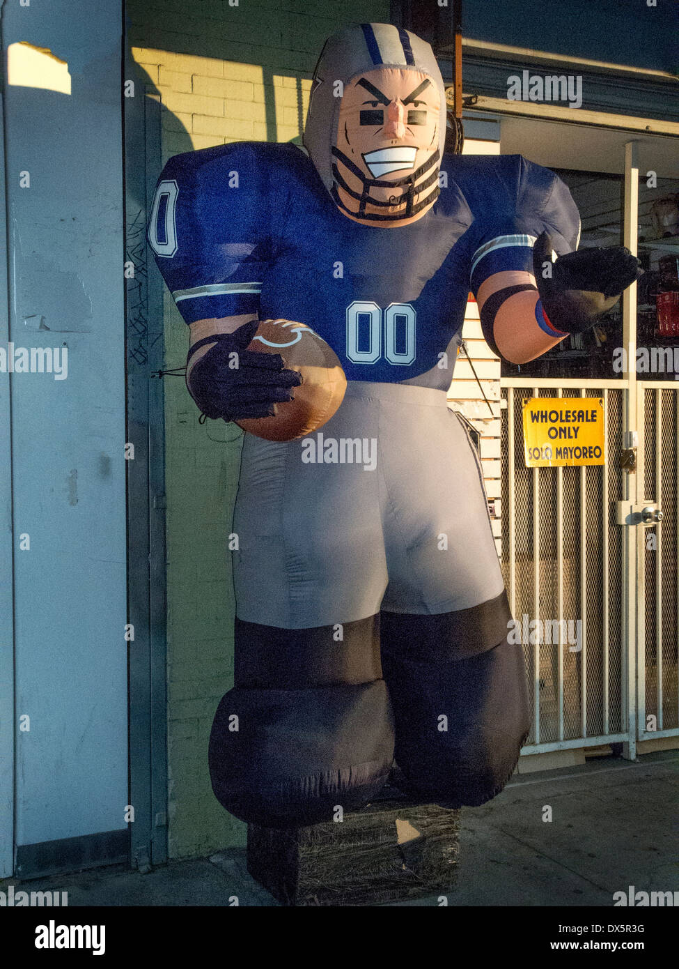 Un pneumatico gonfio giocatore di calcio figura serve come un annuncio pubblicitario nel Los Angeles indumento distretto. Foto Stock
