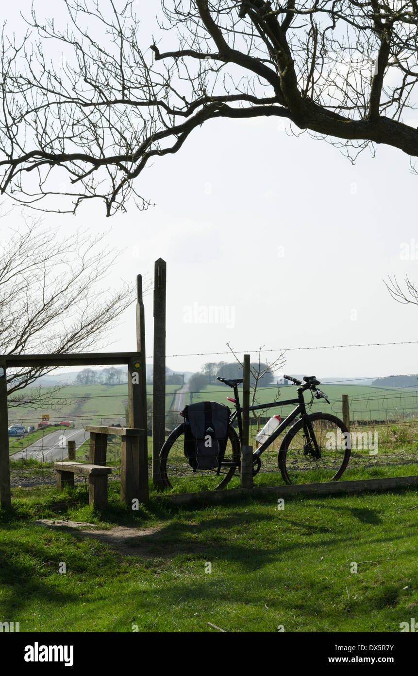 Un nero in cyclo-touring bike contro un stile sul Carlisle a Newcastle strada romana Foto Stock