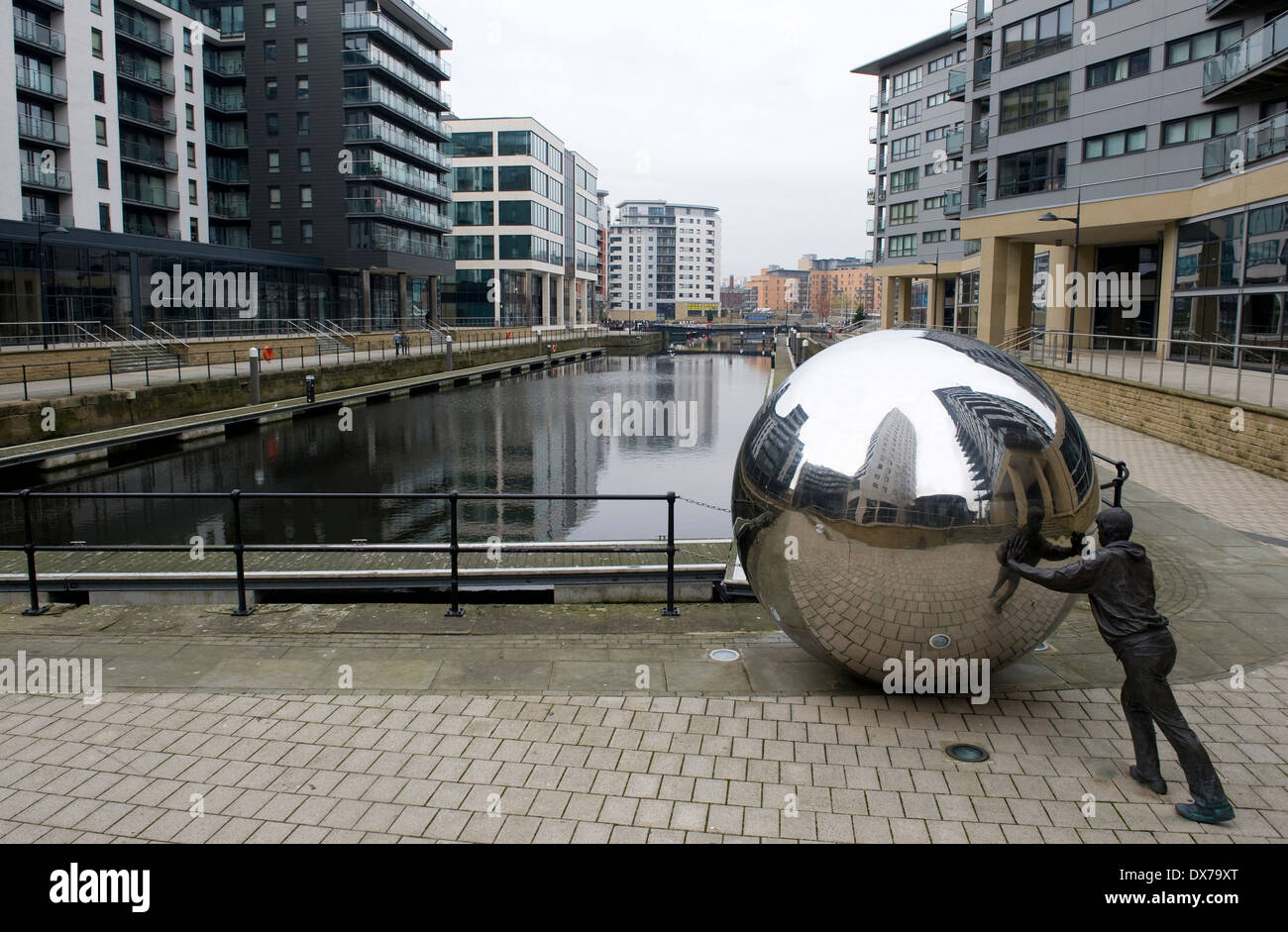 Scultura nel nuovo Dock, precedentemente Clarence Dock, Leeds, che mostra la vita di bronzo di dimensioni figura spinge una sfera di acciaio inossidabile. Foto Stock