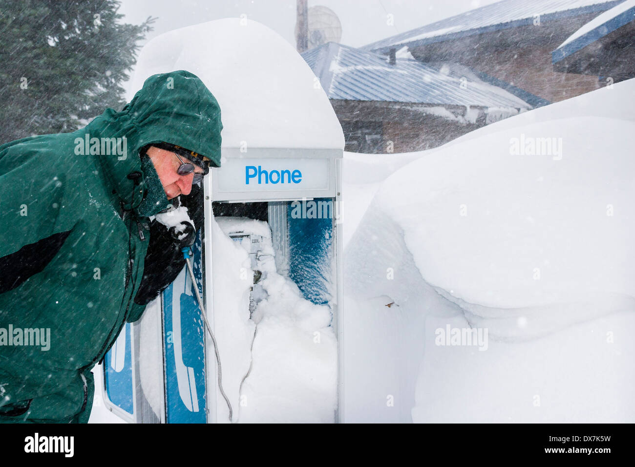 Un uomo parla su una coperta di neve publifon nella tempesta di neve. Foto Stock