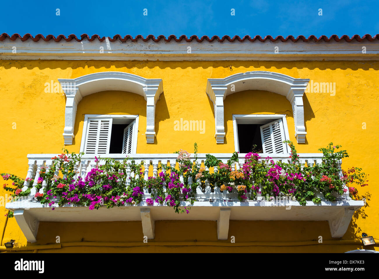 Storica in giallo e bianco balcone a Cartagena, Colombia con fiori colorati Foto Stock